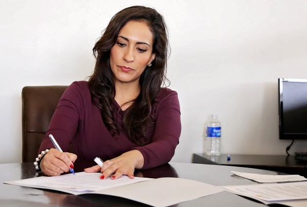 woman at table signing papers for leadership course