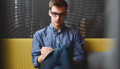 man writing notes sitting on a sofa man writing notes sitting on a sofa